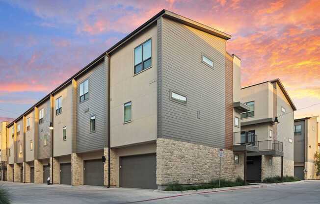 A modern apartment building with a sunset sky in the background.