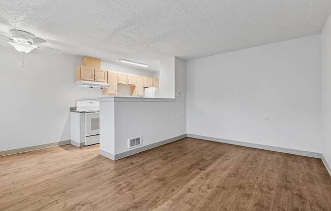 A kitchen with white appliances and wooden floors.