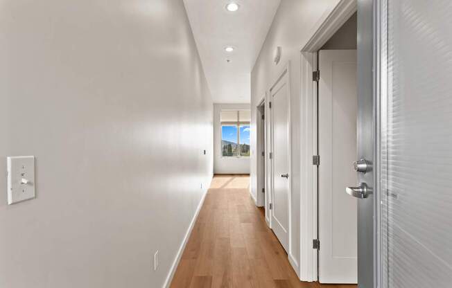 A long hallway with white walls and wood floors.