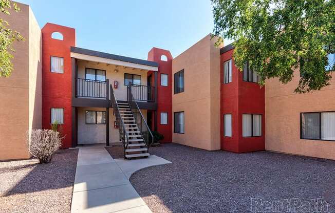 A red and beige building with a staircase leading to the entrance.