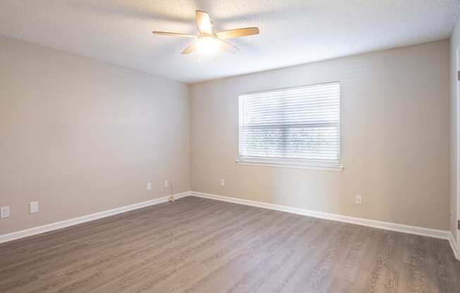 an empty living room with wood floors and a ceiling fan