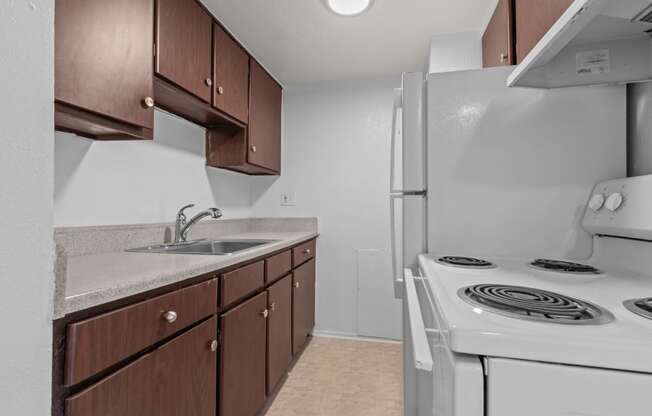 an empty kitchen with a stove refrigerator and sink