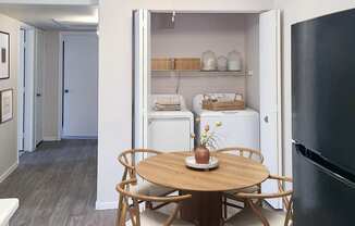 a small table with four chairs in a kitchen with a refrigerator and washer and dryer