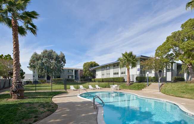 A swimming pool surrounded by palm trees and a building in the background.