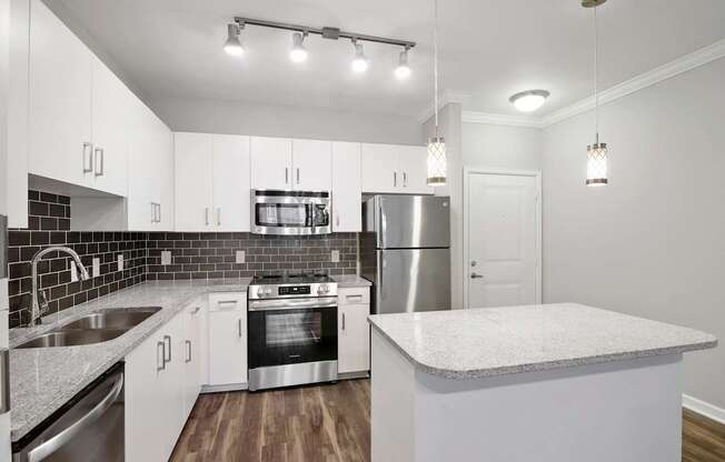 A modern kitchen with white cabinets and stainless steel appliances.