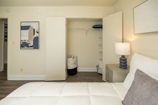 A bedroom with a white bed and a painting on the wall.