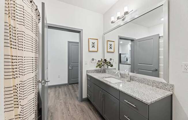 A bathroom with a sink, mirror, and a shower curtain.