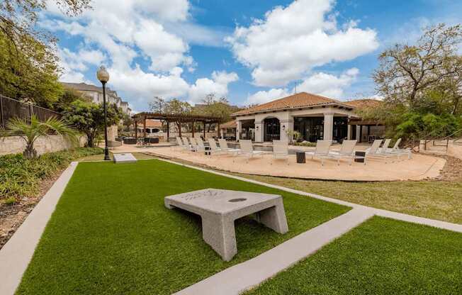 A park with a grassy area and a concrete bench.