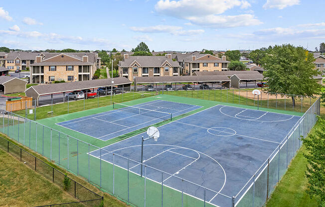 a tennis court with apartments in the background