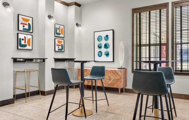 a bar area with stools and tables and artwork on the wall