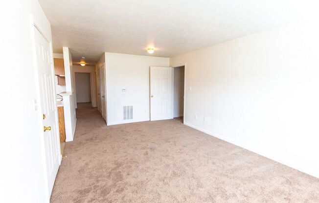 An empty living room with a kitchen in the background at Maple Tree Apartments in LaPorte, IN
