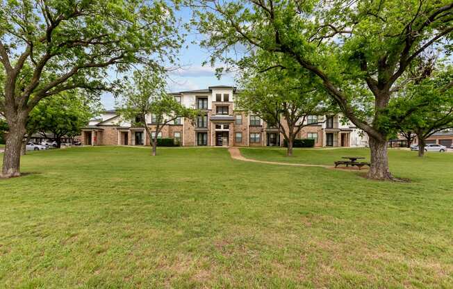 A grassy area with trees and a building in the background.
