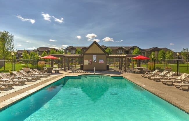 A resort style pool with chaise lounge chairs and umbrellas