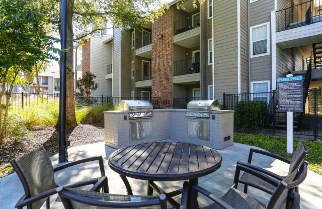 a patio with a grill and a table in front of an apartment building