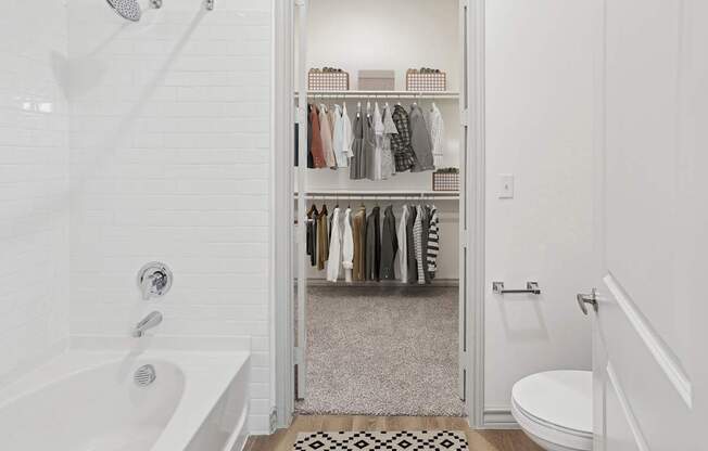 A white bathroom with a walk in closet.