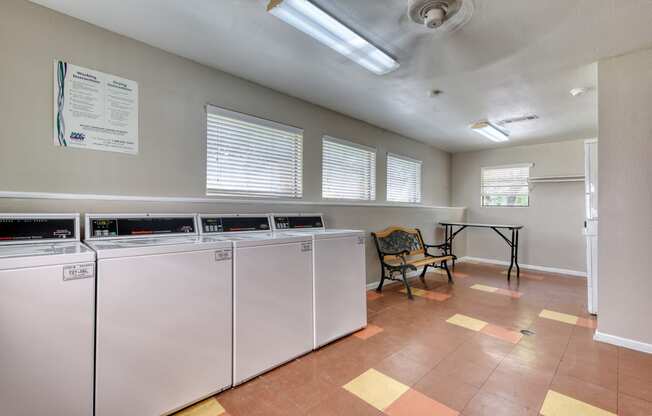 a laundry room with two washers and a table with a chair