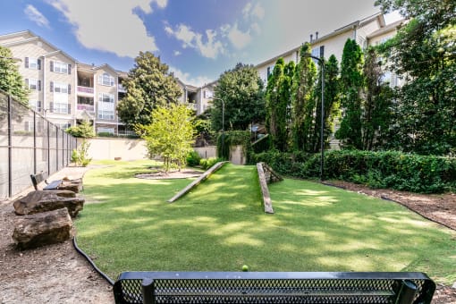 a backyard with a grass lawn and trees and a bench