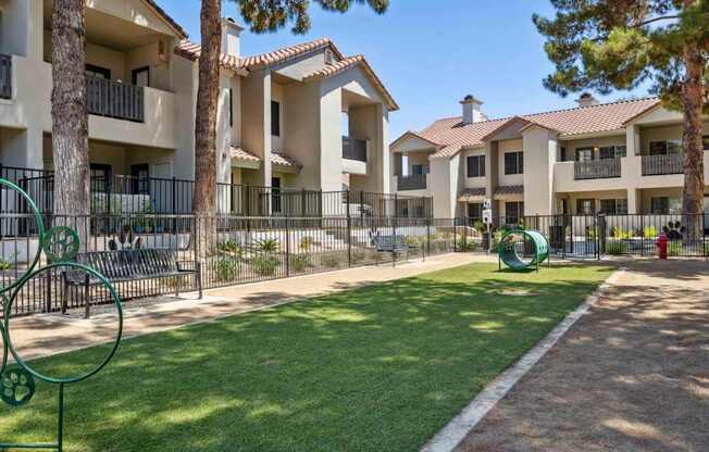A sunny day at a residential complex with a playground and green lawn.