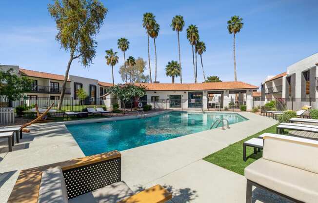 a swimming pool with lounge chairs and palm trees in the background