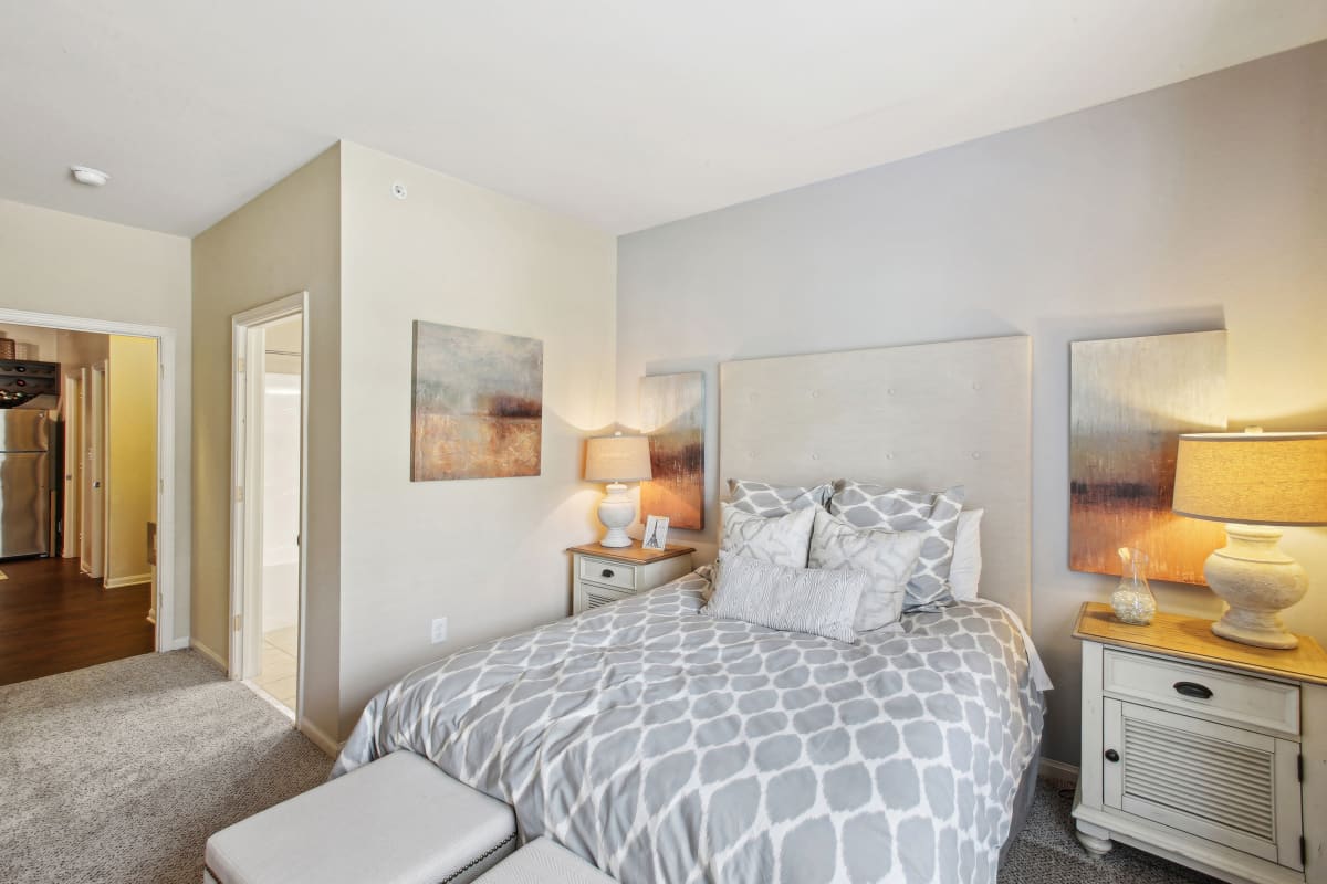 a bedroom with a bed and two night stands and a door to a bathroom