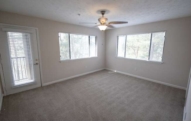 an empty bed room with a ceiling fan and three windows with natural sunlight at Wynnwood Vinings Atlanta