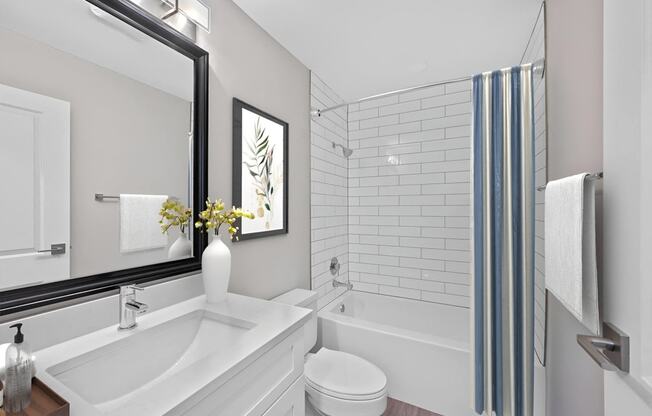 a white bathroom with a large mirror and a tub and a sink