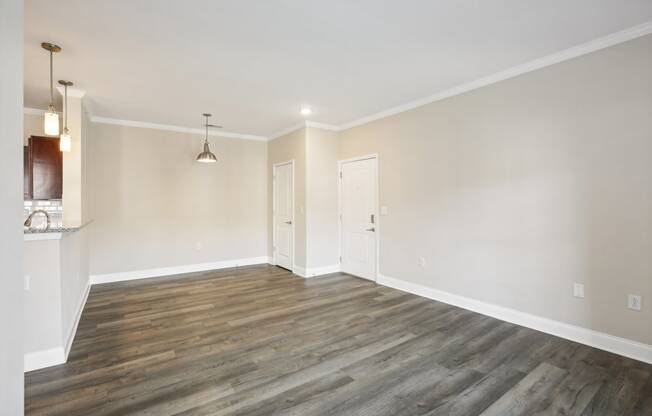 an empty living room with wood floors and white walls