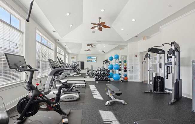 A gym with a variety of exercise equipment including treadmills, stationary bikes, and weight machines.