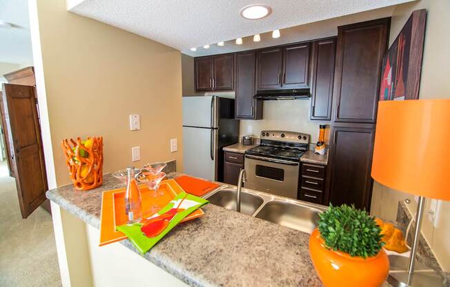 A kitchen with a refrigerator, oven, and sink.