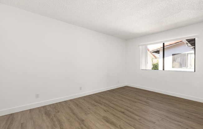 Empty room with wooden floor and a window.