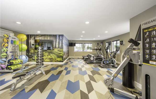 a home gym with a mural of a forest on the wall