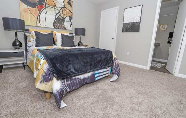 A cypress bedroom with a bed, two lamps, and a painting on the wall at The Marq in Shreveport, LA