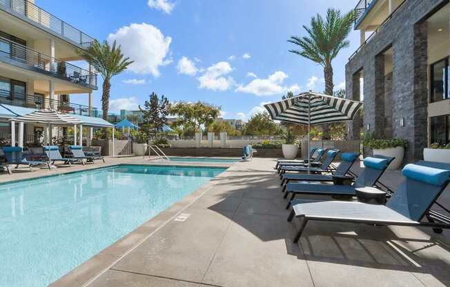 A pool area with sun loungers and a striped umbrella.