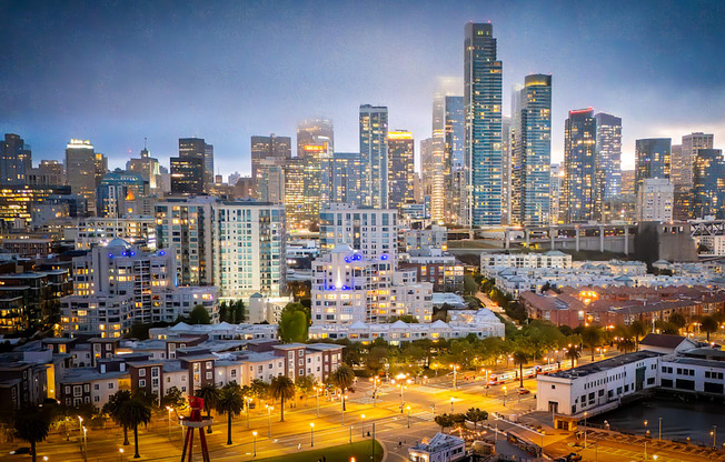 A cityscape at dusk with buildings illuminated against a darkening sky.