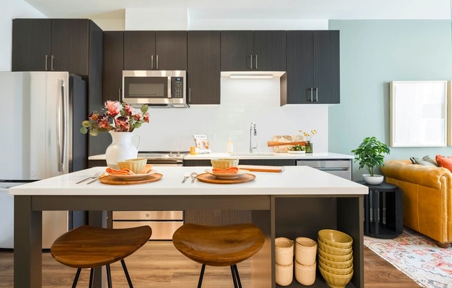 A modern kitchen with a dining table set for two.at The Vale at the Parks, Washington, DC 20012