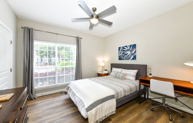 Bedroom with large window, ceiling fan, and wood plank flooring