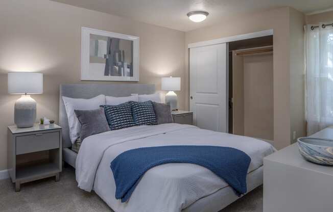 a bedroom with a bed and two nightstands and a door to a bathroom