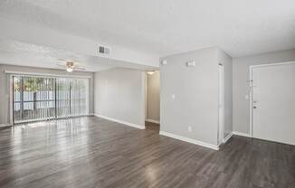 A spacious room with wooden floors and white walls.
