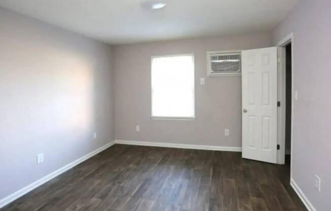 an empty living room with wood floors and a white door