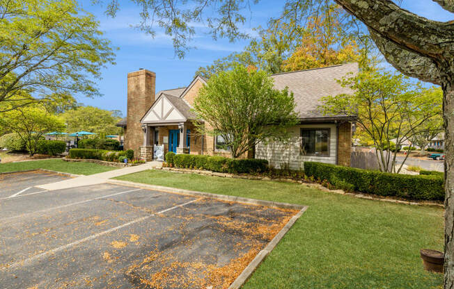 the front of a house with a asphalt driveway and lawn and trees