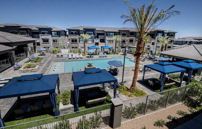 A pool surrounded by blue umbrellas and chairs.