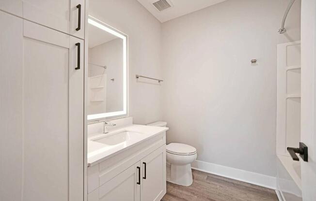 A white bathroom with a toilet, sink, and mirror.