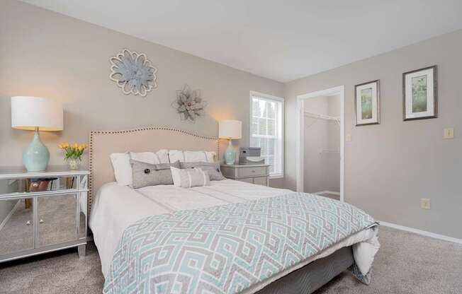 A bedroom with a large bed and a nightstand with a lamp.