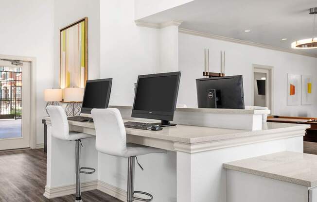 A white desk with two monitors and a laptop.