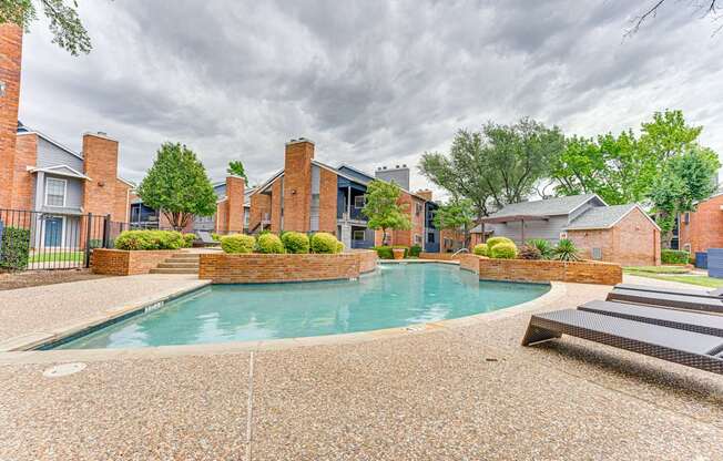 A swimming pool surrounded by a brick wall and a concrete patio.