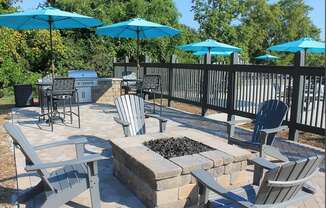 a patio with chairs and umbrellas and a fire pit