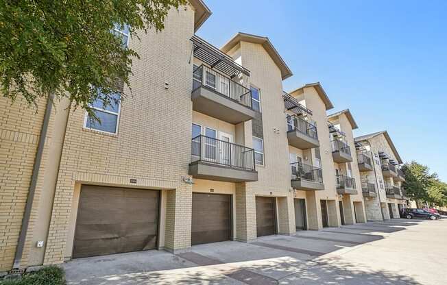A row of apartment buildings with balconies and garage doors.