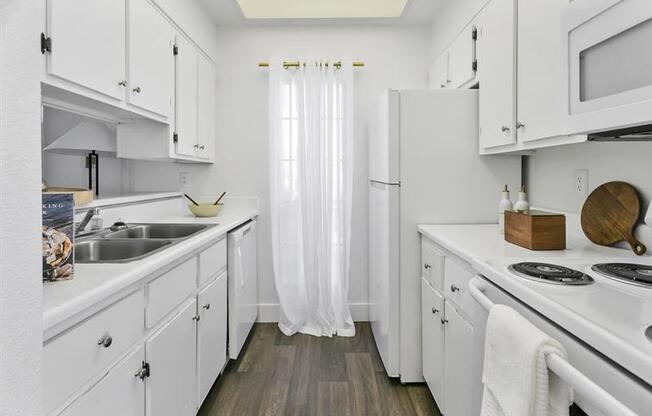 A white kitchen with wooden floors and white cabinets.