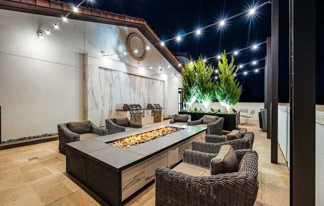 Rooftop terrace with fire pit lounge, string lights, and plush seating designed for cozy evenings