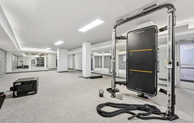 A gym with a rope, a bench, and a black screen with a yellow line.